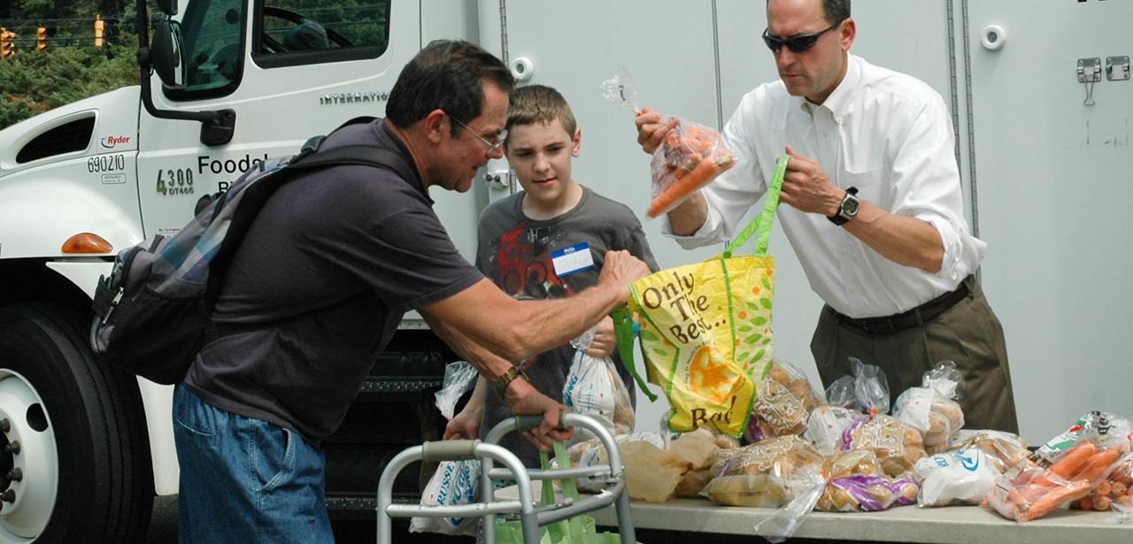 boy and man giving food to a handicapped man